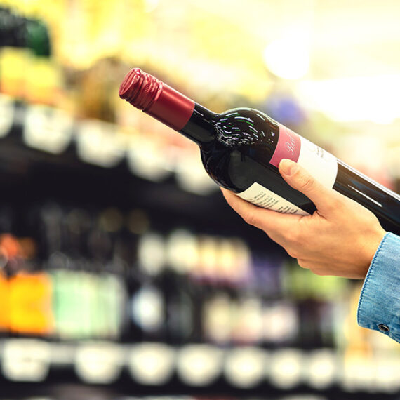 Woman-in-bottle-shop-looking-at-label-of-red-wine-bottle